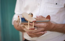 Load image into Gallery viewer, Person holding a wooden toy airplane with a blurred background
